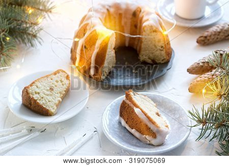 Pie With Raisins And Icing From Powdered Sugar On The Background Of Fir Branches And Garlands. Rusti