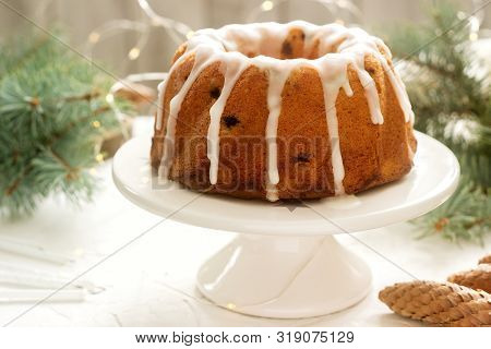 Pie With Raisins And Icing From Powdered Sugar On The Background Of Fir Branches And Garlands. Rusti