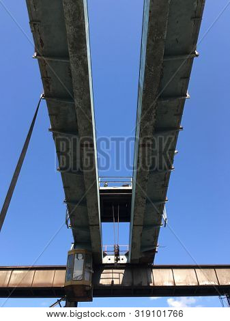 Old abandoned multi-ton crane beam against a clear blue sky. Industrial background.