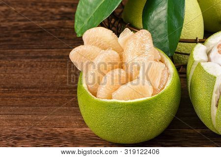 Fresh Peeled Pomelo, Grapefruit, Shaddock With Green Leaves On Dark Wooden Plank Table. Seasonal Fru