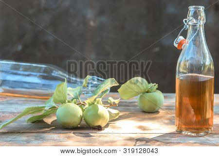 Apple Cider Poured Into Bottles. Glasses Filled With Apple Cider Vinegar Stand On An Old Vintage Tab