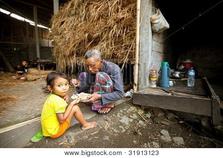 BALI - 3 aprile: Unidentified povero bambino mangia con suo padre durante una pausa lavorando nella fattoria 