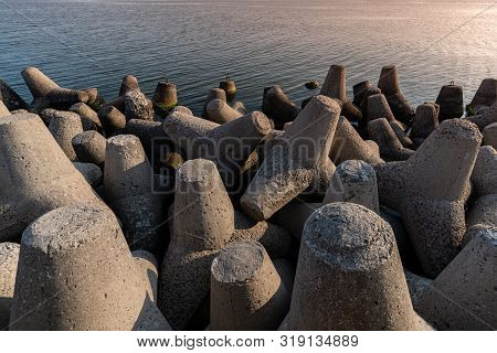 Tetrapod Breakwaters In Sea Water. Beautiful Sunset Seascape With Concrete Tetrapodes For Protect Co