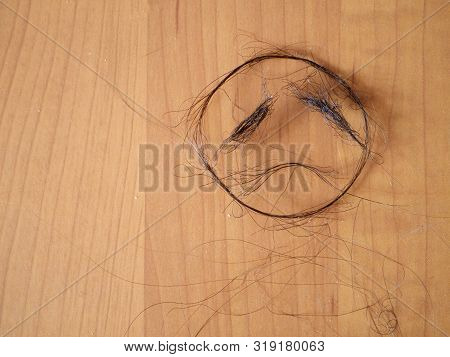 Ock Of Black Hair Isolated On Wooden Background. Hair Loss Concept.