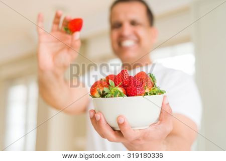 Middle age man eating straweberry at home