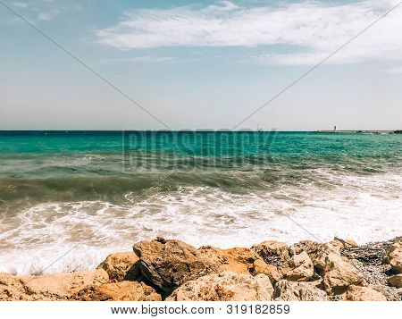 Rocky Sea Shore With Splaches Of Waves. Mediterranean Sea Coast. Seascape. Beautiful Day, Blue Sky, 