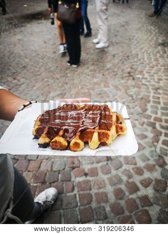 Hand Of A Girl Holding A Chocolate Waffle In A Street Of Bruges