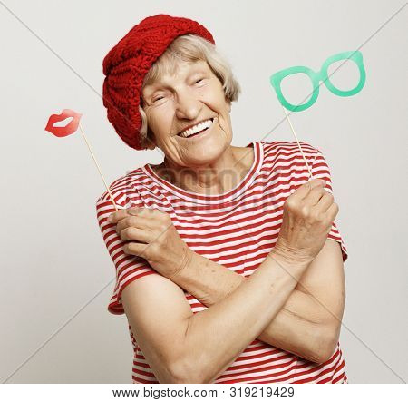 funny grandmother wearing red clothes holding falce glasses and ready for party
