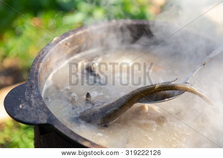 Fish Soup. Cooking Delicious Soup In A Large Cauldron On The Fire.