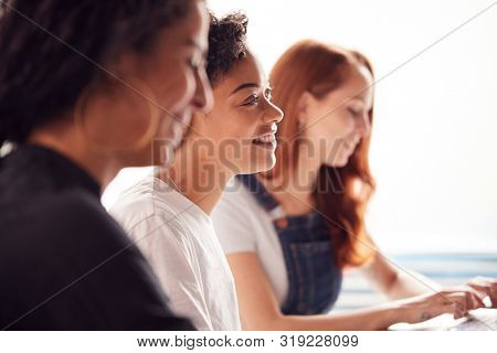 Team Of Young Businesswomen In Meeting Around Table In Modern Workspace