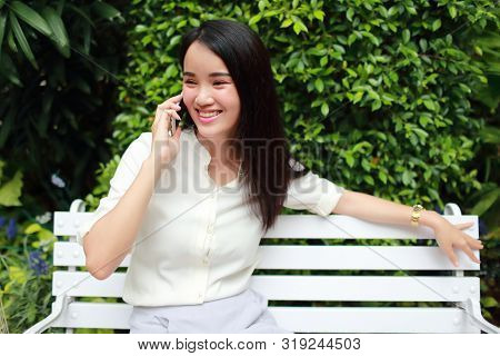 Young And Cute Asian Women Sitting And Using Cell Phone During Holiday