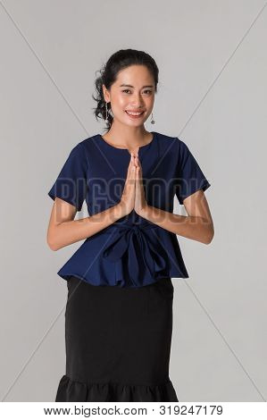 Beautiful Asian Businesswoman Standing And Is Posing Wai, It Is The Thai Traditional On White Grey B