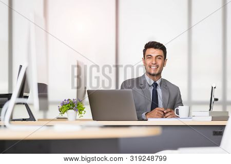 Handsome Caucasian Businessman Holding A Pen In His Hands, On A Table With A Notebook And A Coffee M