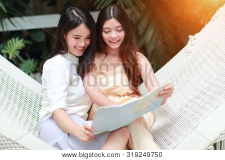Young And Cute Asian Women Lying In A Hammock And Searching Location In A Map During Holiday