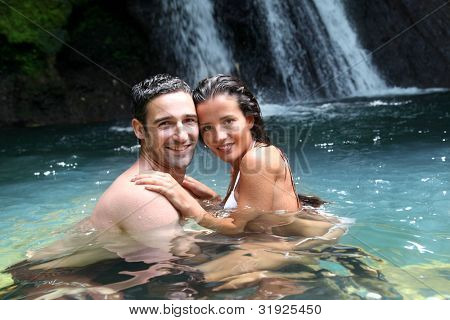 Happy couple bathing near waterfall in island