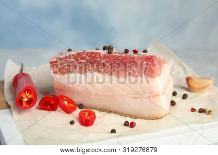 Composition With Pork Fatback And Spices On Board Against Blue Background