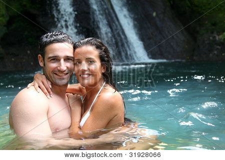 Happy couple bathing near waterfall in island