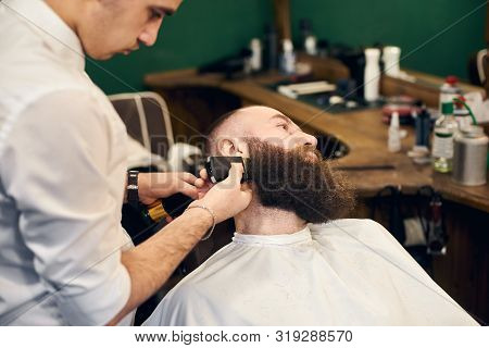 Adult Client Man In Hairdresser Chair Throwing Back His Head During Barber Styling Clients Beard Wit