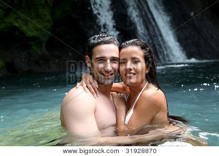 Happy couple bathing near waterfall in island