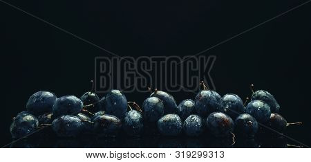 Beautiful Fresh Blue Pulms On A Black Glass Table And Dark Background.