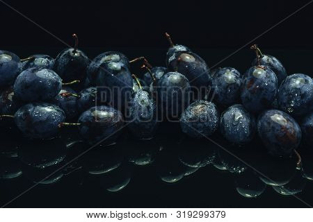 Beautiful Fresh Blue Pulms On A Black Glass Table And Dark Background.