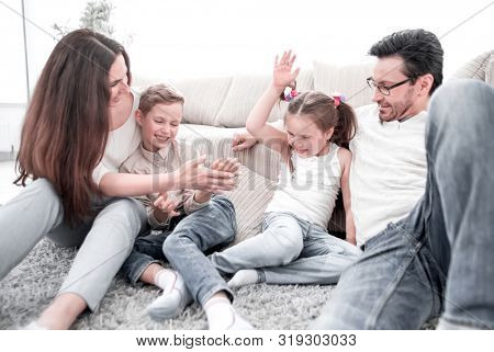 parents play with children sitting on the carpet in the living room