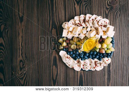 Assortment of cheeses, and fruit on a wooden table. Top view. Free space for text.