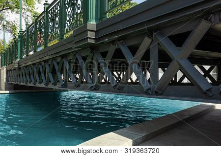 Bridge Across Water Channel. Metal Frame Structure Over Pure Calm River. Modern Urban City Landscape