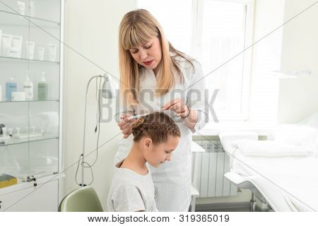 Doctor Trichologist Examines The Hair Of A Little Girl Patient In His Office.