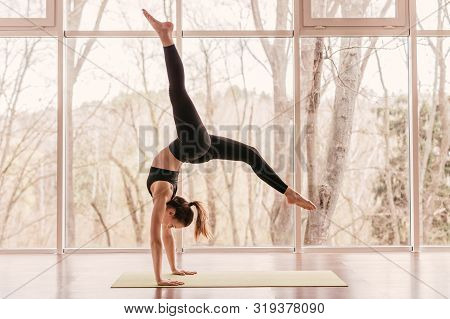 Side View Of Strong Young Lady In Sportswear Performing Handstand With Splits During Morning Yoga Ro