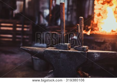 Dark Stithy Workshop With Hammer On Anvil At Firs Plan And Fire In Stove At Background.