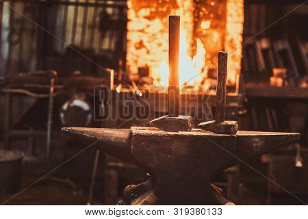 Dark Stithy Workshop With Hammer On Anvil At Firs Plan And Fire In Stove At Background.