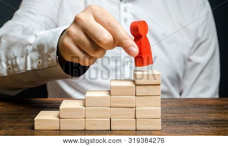 A Man Puts A Red Human Figure On Top Of The Stairs. Career Growth, Improvement Of Skills. Promotion 