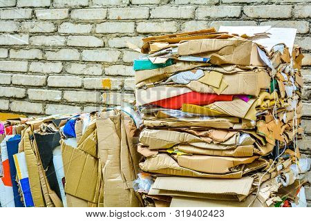 Bundle Of Wastepaper Cardboard To Be Recycled. Paper Cardboard Is Bundled Into Bale. Scene Is Outdoo
