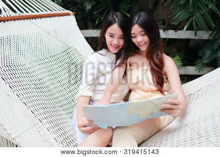 Young And Cute Asian Women Lying In A Hammock And Searching Location In A Map During Holiday
