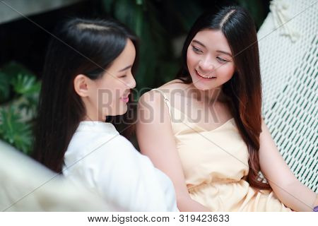 Young And Cute Asian Women Lying In A Hammock And Looking Photo Album During Holiday