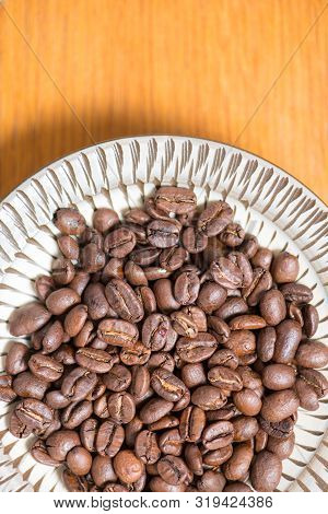 Coffee Beans On A Plate Placed On A Wooden Table.