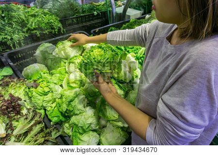 Young Housewife Choosing Fresh Salad At Grocery Store