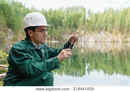 Industrial Ecologist Or Chemist Takes A Sample Of Water From Lake At The Site Of A Flooded Quarry