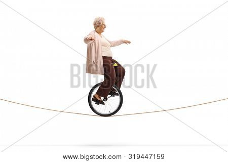 Full length profile shot of a senior woman riding a mono-cycle on a rope isolated on white background
