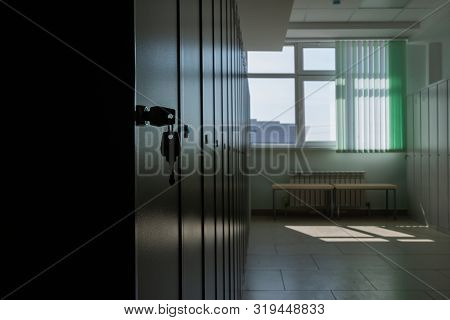 The Key Is In The Lock Of The Outer Door Of The Metal Cabinet. Silhouette Opposite A Bright Window. 