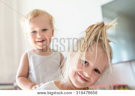 Cute Adorable Blond Caucaian Little Sister Hugging Her Toddler Brother.couple Of Cheerful Sibling Pl