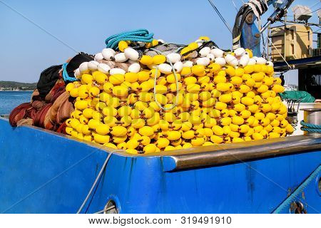Yellow Floats On The Pile, Covering Fishing Nets On The Blue Boat In The Summer Sun. Fishing Floats 