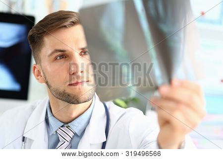 Portrait Of Thoughtful Doc Examining X-ray Picture. Concentrated Physician Making Diagnosis. Medical