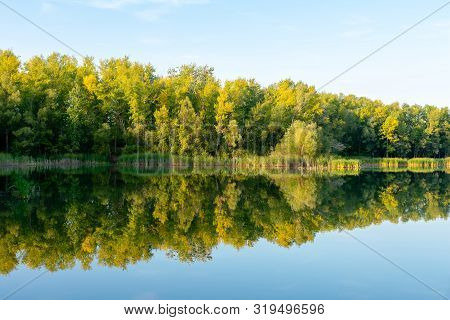 Autumn Forest Is Reflected In The Water Of A River. Colorful Foliage Over Lake With Beautiful Woods.