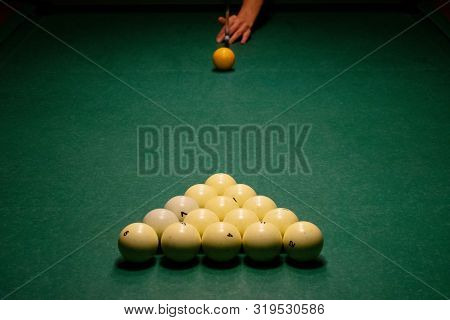 The Arm Of The Billiards Player Preparing To Strike. Ivory White Billiard Balls On A Green Pool Tabl