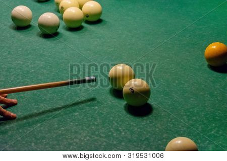 The Arm Of The Billiards Player Preparing To Strike. Ivory White Billiard Balls On A Green Pool Tabl