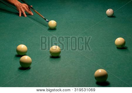 The Arm Of The Billiards Player Preparing To Strike. Ivory White Billiard Balls On A Green Pool Tabl