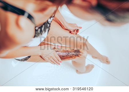 Slim Young Woman In A Bright Silk Pajamas Scrabs Her Leg Sitting In A Big Beautiful Bright Bath. Ski