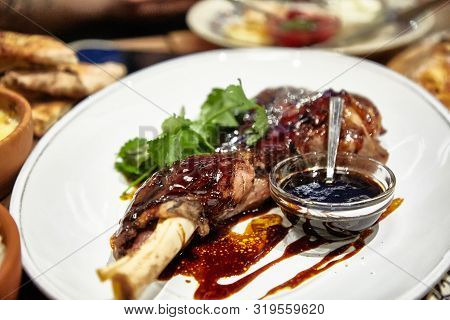 Stewed Leg Rabbit Or Duck Is On A Plate With Sauce.
